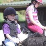 children riding ponies and smiling