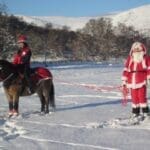 Santa holding horse as people ride the horse