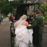 Bride and Groom climbing onto the back of the carriage